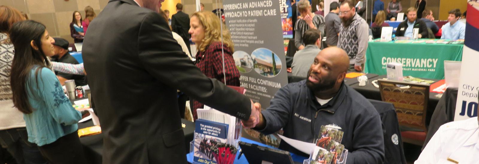 A student shakes hands with a recruiter at the Spring Career Fair
